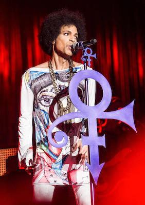 Prince standing behind his symbol